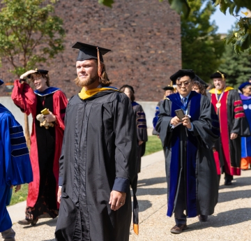 Faculty members walking in academic regalia