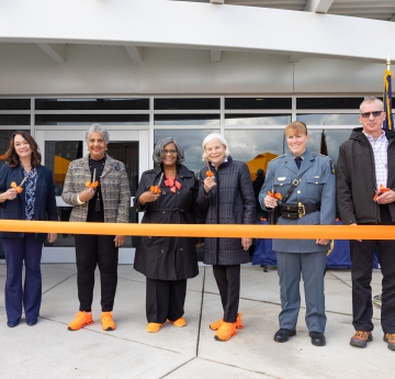 Group of seven people cutting ceremonial ribbon