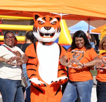 Three people with bengal mascot