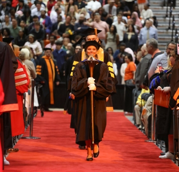 Faculty member walking with mace