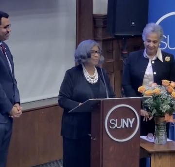 Bonita R. Durand, Ph.D., standing at podium with SUNY Chancellor King and SUNY Trustee Lewin