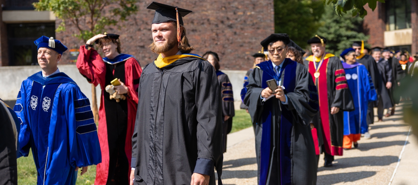 Faculty members walking in academic regalia