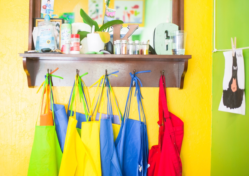 Colorful aprons haning underneath a set of art supplies